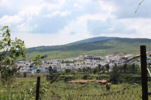 Fotografía de lejos a casas abandonadas de Tlajomulco con áreas verdes y el cielo medio nublado