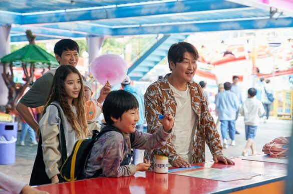 Un hombre adulto, un hombre joven y mujer joven con niño como familia en película Broker jugando en una feria