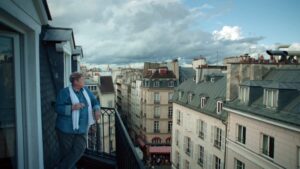 Mujer en un balcón en ciudad europea de fondo