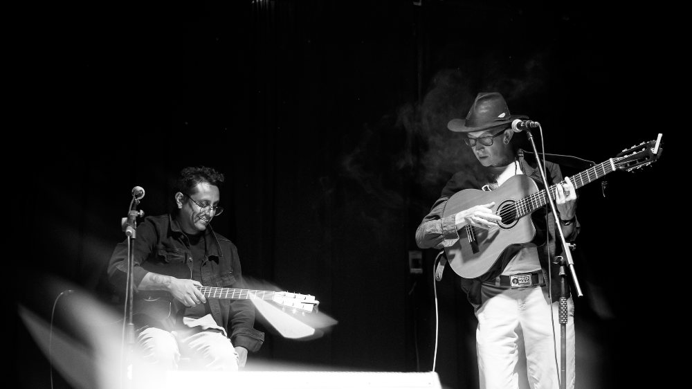Dos hombres en escenario tocando guitarra