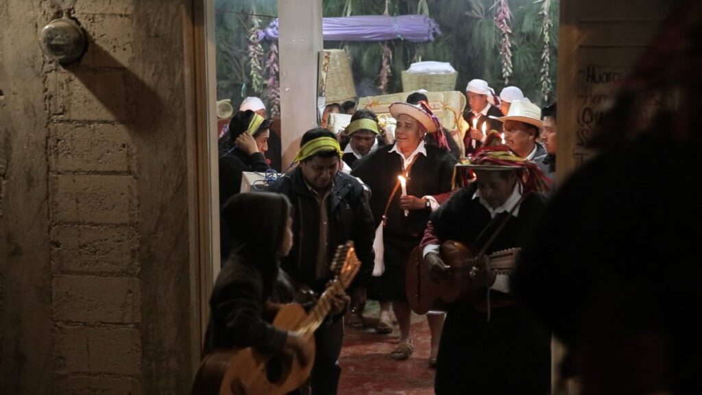 Hombres con túnicas negras procesión niño con guitarra enfrente