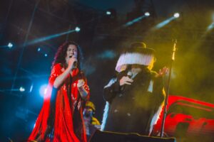 Dos personas cantando, mujer y hombre, vestido rojo, traje regional