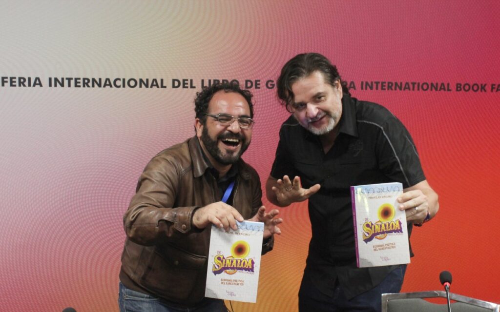 Dos hombres en pose de luchador sosteniendo un libro