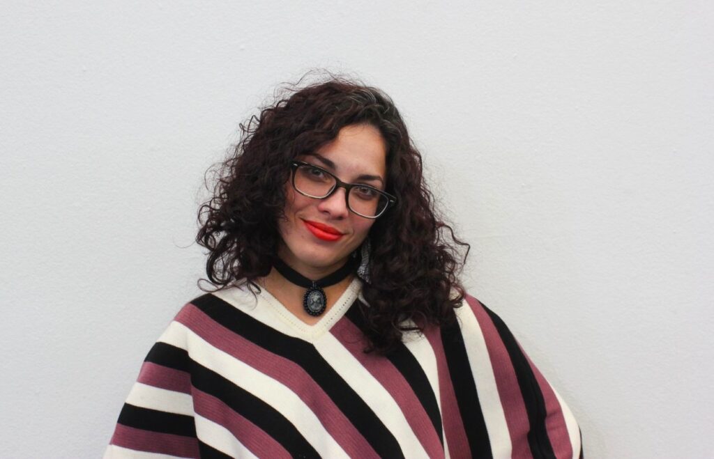 Mujer joven cabello negro con lentes y suéter rayado