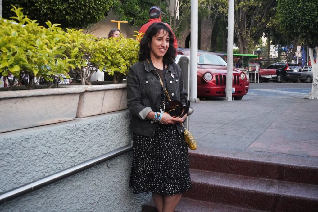 Mujer con vestido negro y chaqueta con un premio en las manos