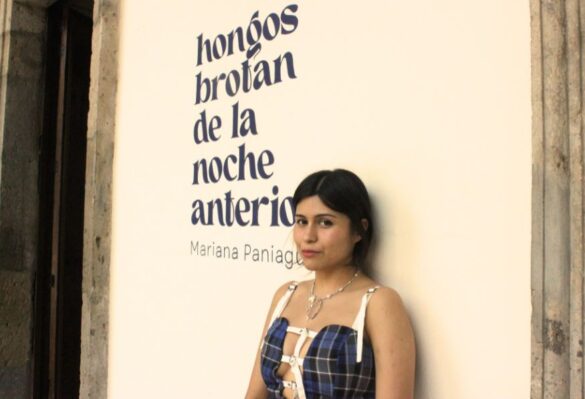 Mariana Paniagua mujer cabello negro vestido morado recargada en pared con letrero hongos brotan de la noche anterior