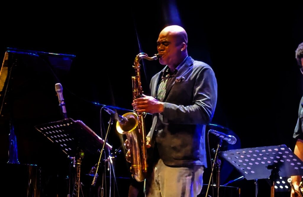 Wayne Escoffery (3) Hombre sin cabello con camisa tocando el saxofón en el escenario