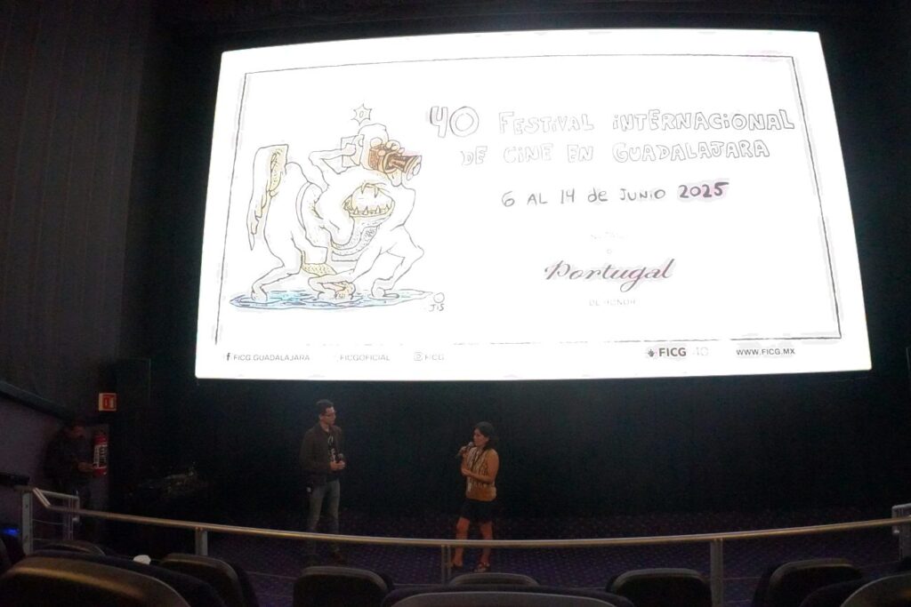Pantalla de cine arriba debajo dos personas con micrófonos un hombre y una mujer
