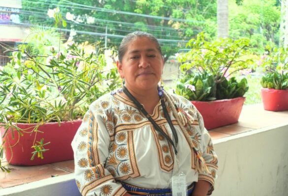 Mujer parada ante foto blusa blanca plantas detrás es Leticia Gallardo