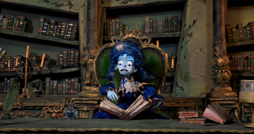 Muñeca de mujer azul en biblioteca con un libro Soy Frankelda