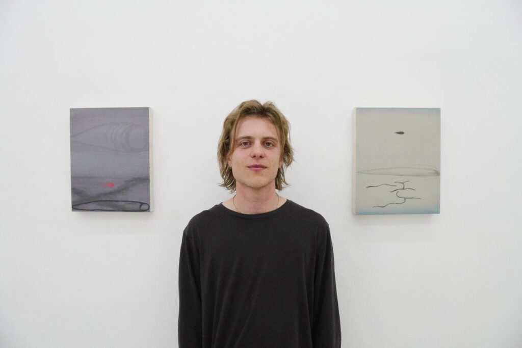 hombre joven suéter negro en medio de pinturas