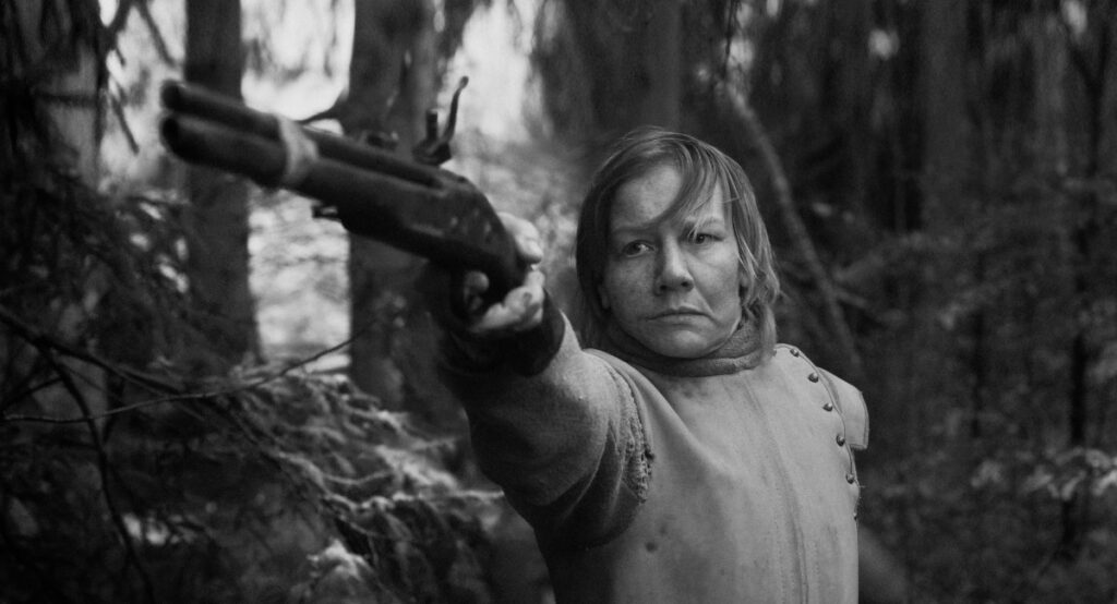 Mujer con una pistola apuntando en el bosque